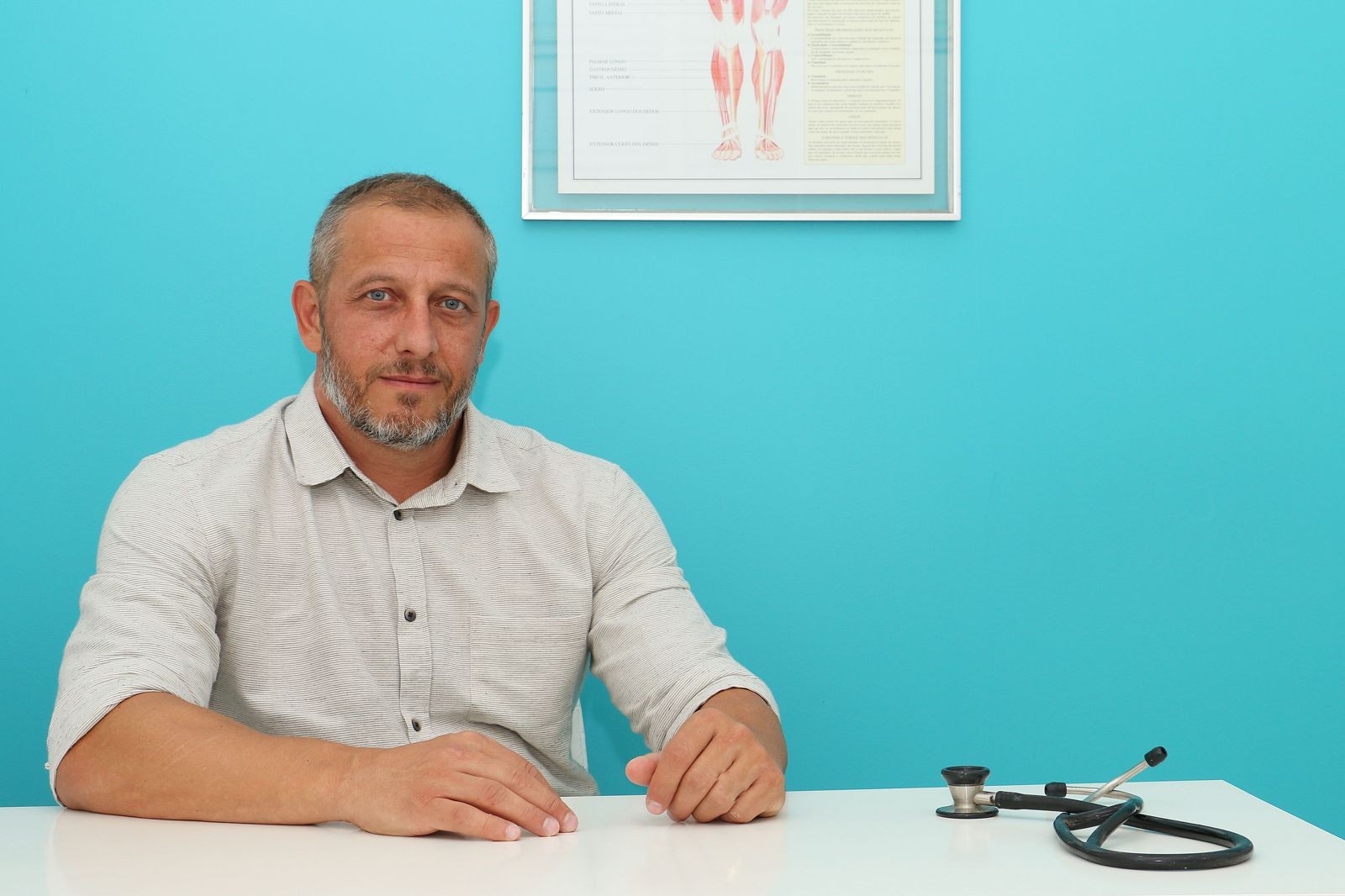 Alexandre sentado à mesa do consultório